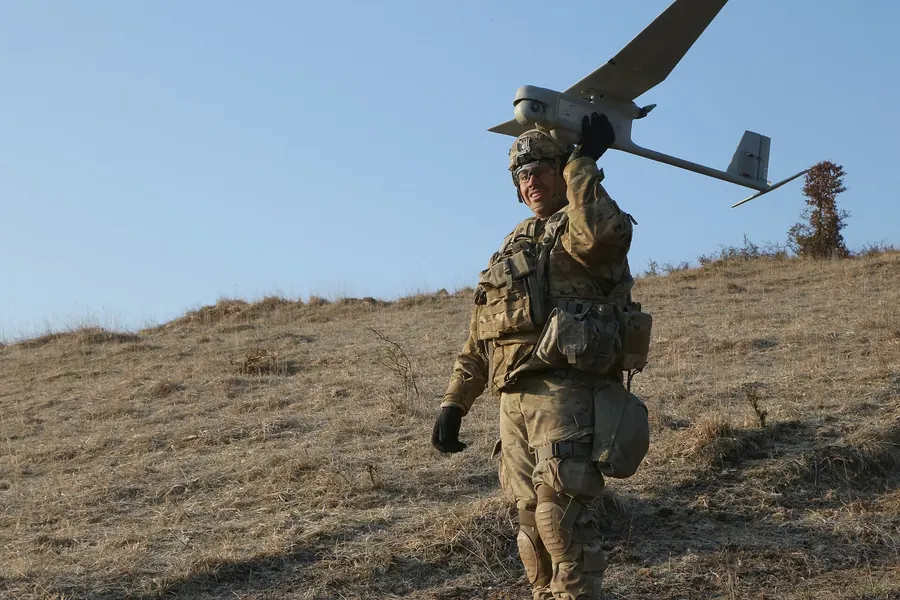 A soldier launching a small drone by hand on a hillside
